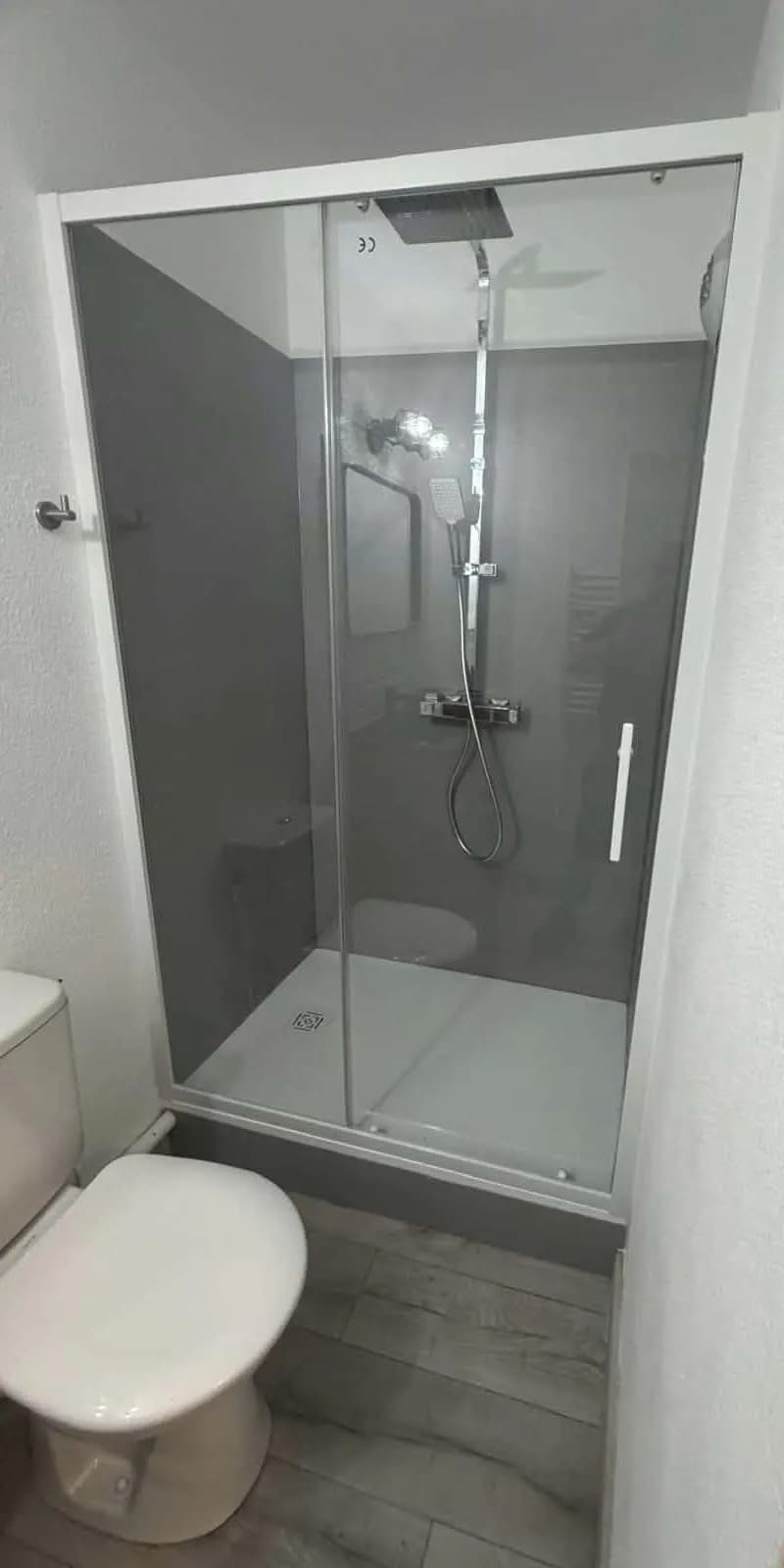 Douche rénovée avec des panneaux muraux gris, un receveur neuf et une paroi coulissante